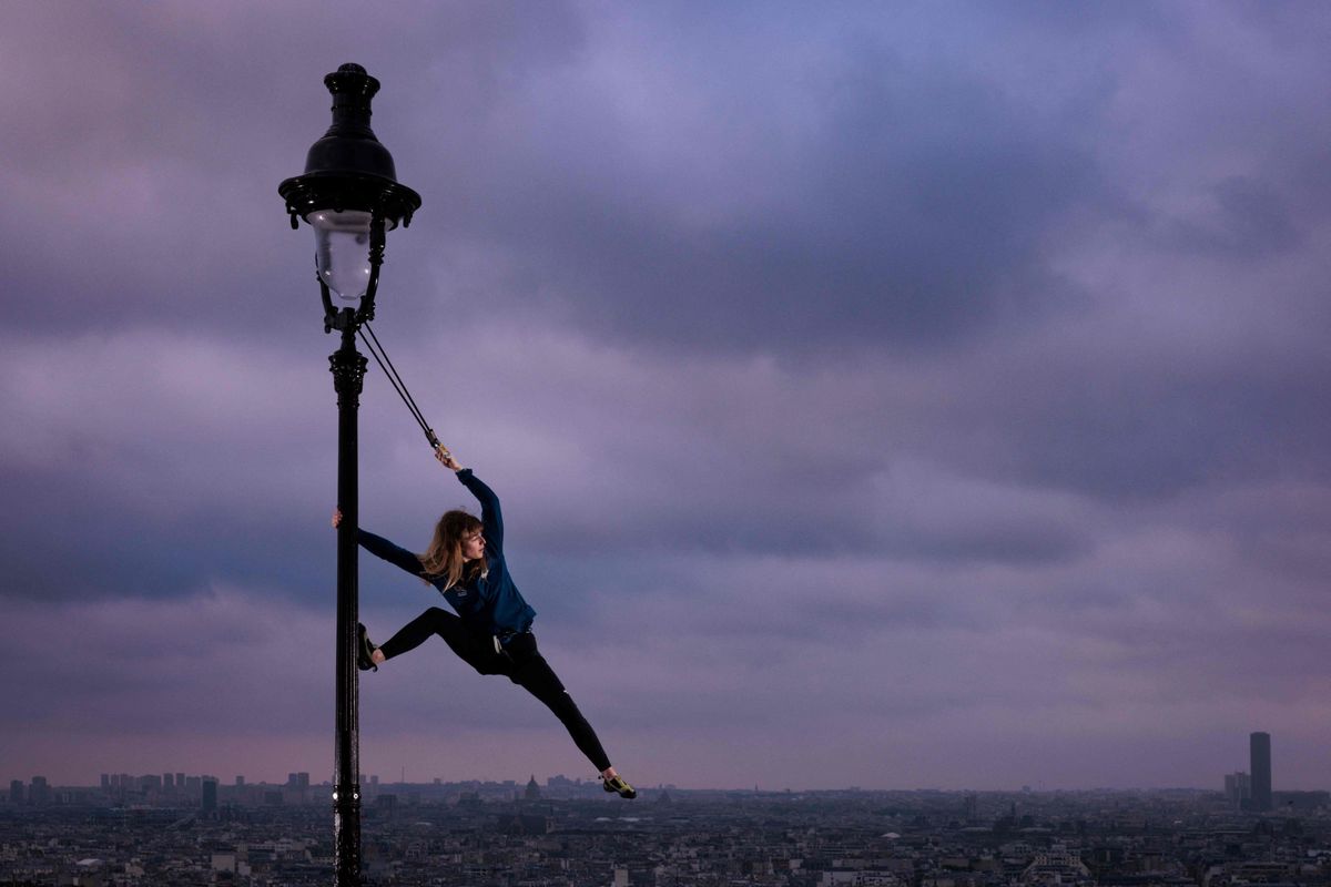 Lighting the Olympic flame: Climber Capucine Viglione climbs a street lamp near the Sacre Coeur in Montmartre.