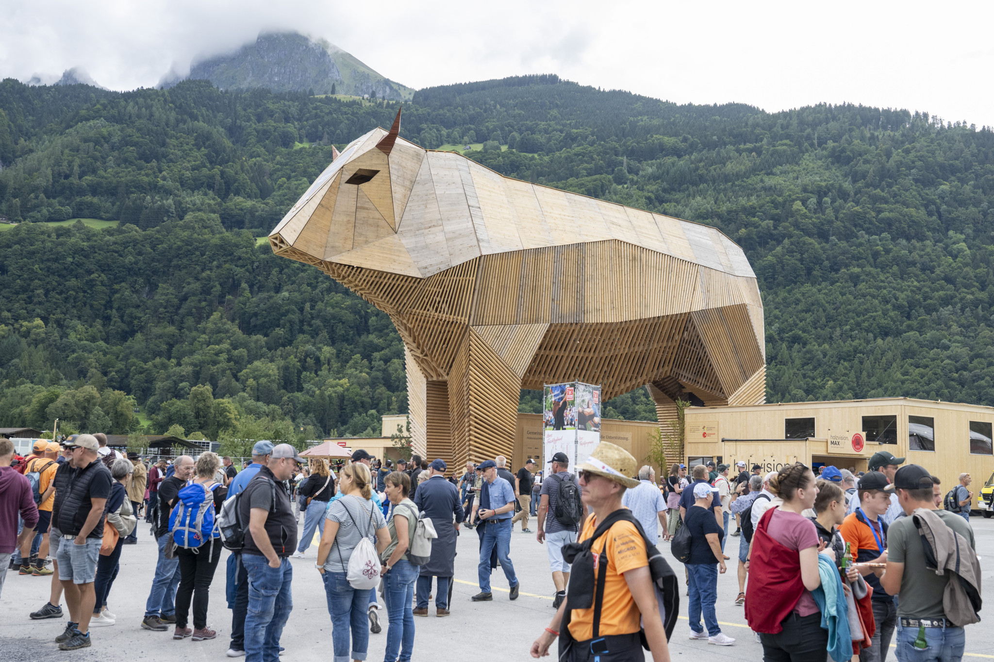 Besucher strömen am Holzstier Max vorbei auf dem ESAF Festgelände beim Eidgenössischen Schwing- und Älplerfest 2025 in Mollis.