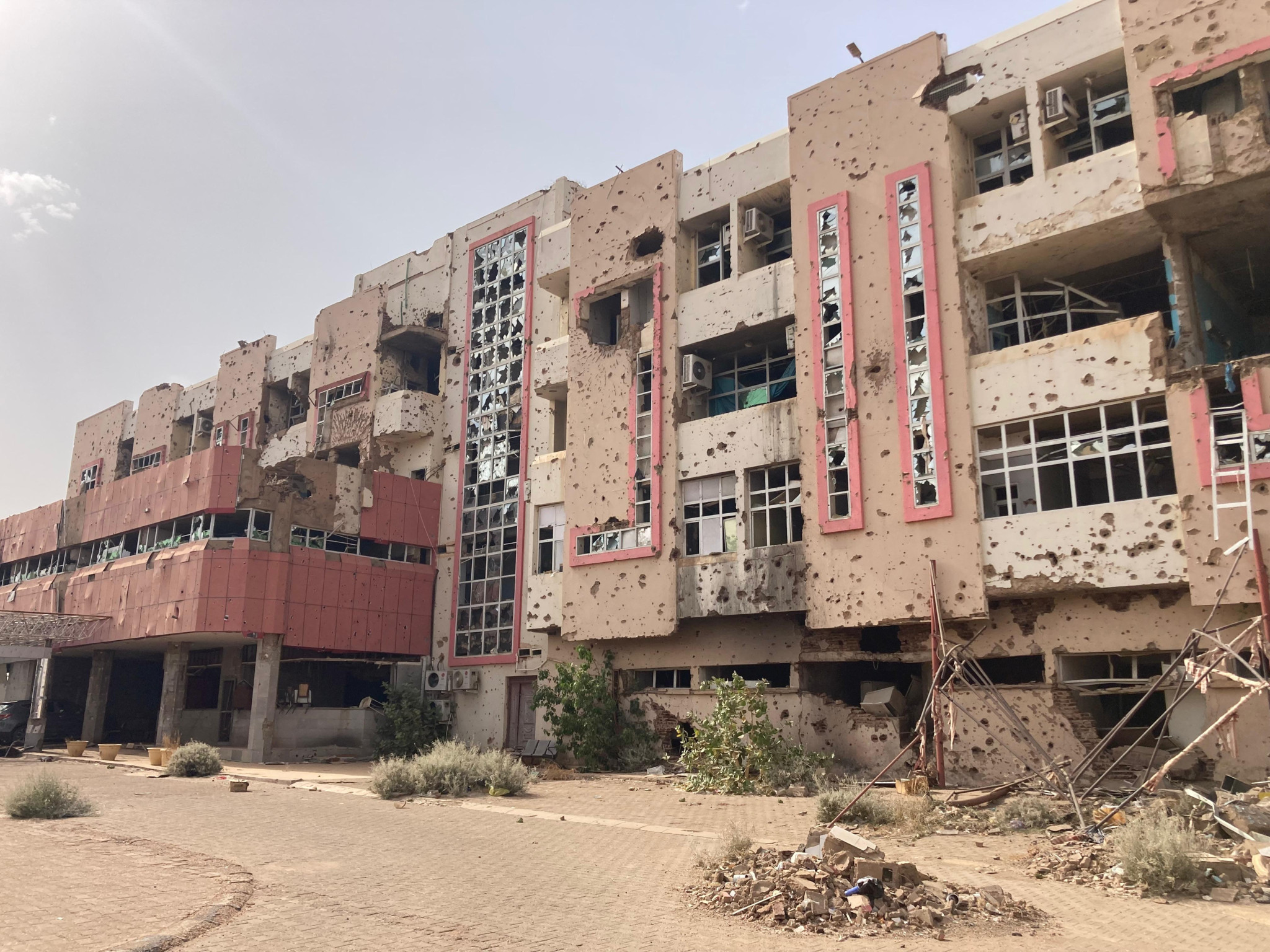 Schwer beschädigtes Spital im Sudan mit eingeschlagenen Fenstern und Einschusslöchern in der Fassade, Kriegsschäden sichtbar.