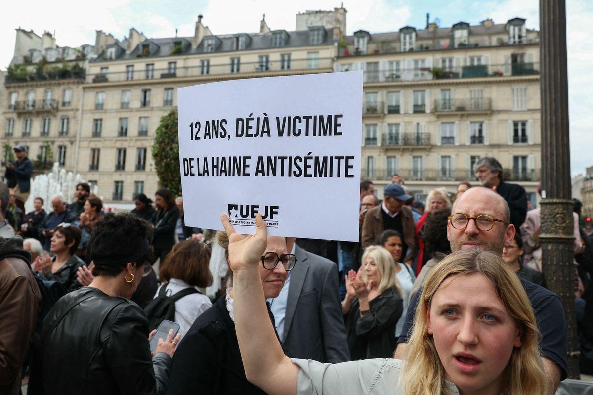 A protester holds a placard which reads as "Twelve year-old and already a victim of antisemitic hate" as she gathers to condemn the alleged anti-semetic gang rape of a 12 year-old girl, at the Paris city hall square on June 19, 2024. In the midst of the general election campaign, political reactions are multiplying after the indictment on June 18, 2024, of two 13-year-olds for gang rape, death threats, anti-Semitic insults and violence against a 12-year-old girl. (Photo by ALAIN JOCARD / AFP)