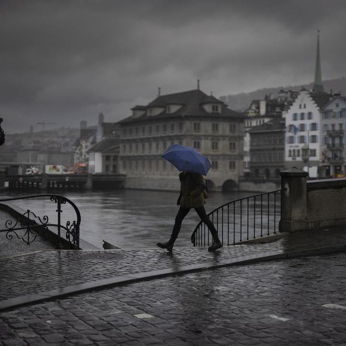 Une femme marche sous la pluie avec un parapluie.