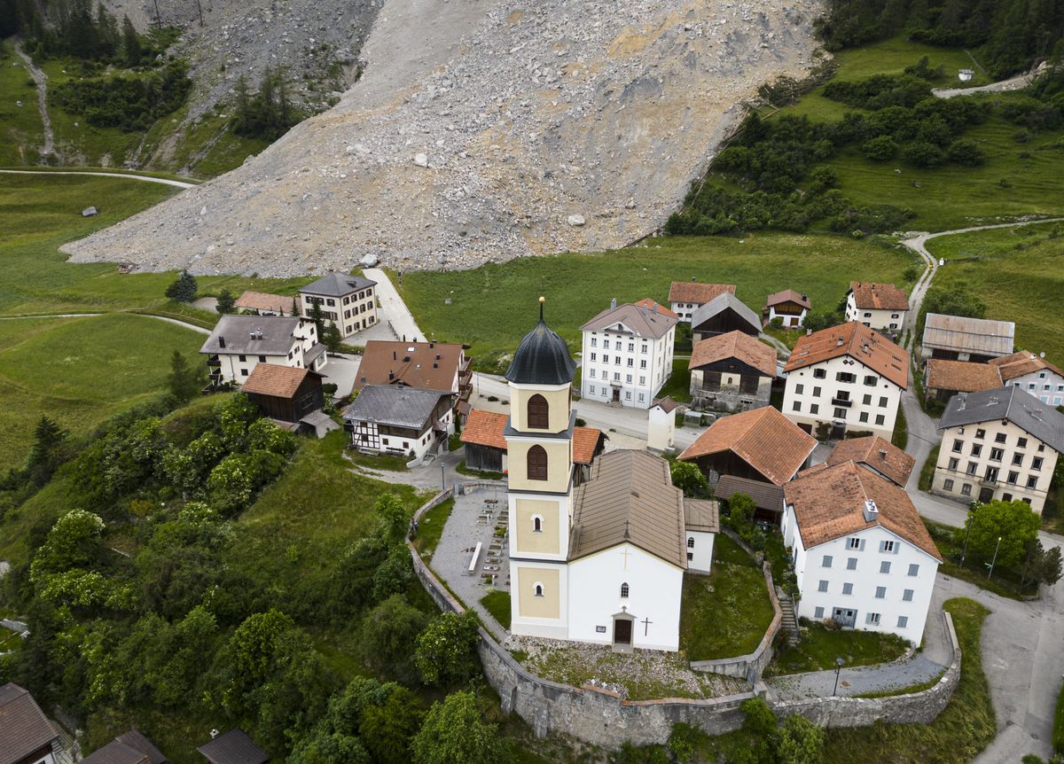 epa10694206 A general view shows the village Brienz-Brinzauls below the rockfall 'Brienzer Rutsch' (L), in Brienz-Brinzauls, Grisons canton, Switzerland, 16 June 2023. An estimate two million cubic metres of rock from the mountain above the village are expected to come loose and crash down to the valley. The village has been evacuated since 12 May. EPA/MICHAEL BUHOLZER