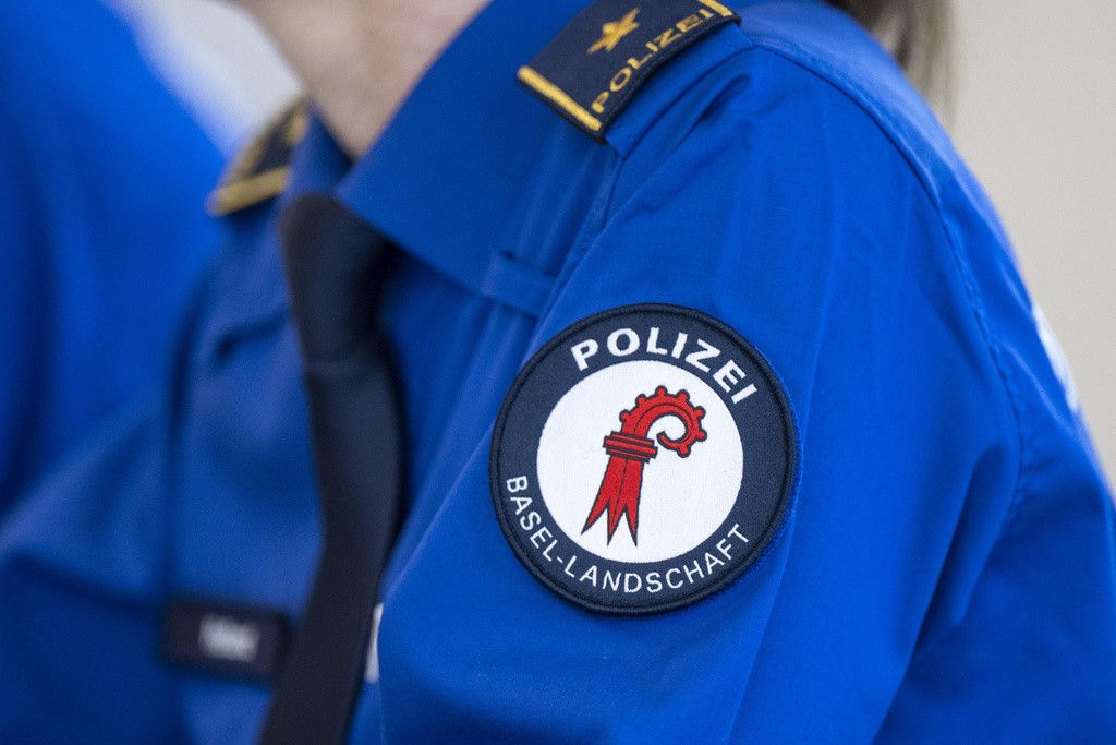 Gros plan sur le bras d'un officier de police en uniforme bleu de Bâle-Campagne, avec un insigne sur le bras.