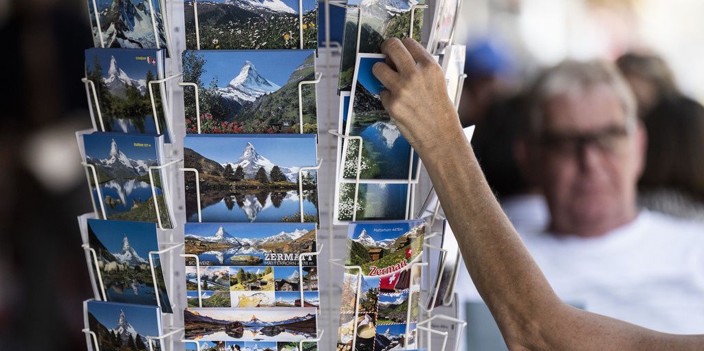 Eine Touristin stöbert in Zermatt in einem Postkartenständer.