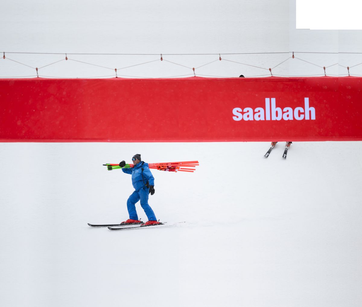 epa11240807 A volunteer carries the gate posts after the men's downhill race was cancelled due to windy weather conditions at the FIS Alpine Skiing World Cup finals in Saalbach Hinterglemm, Austria, 24 March 2024.  EPA/GIAN EHRENZELLER