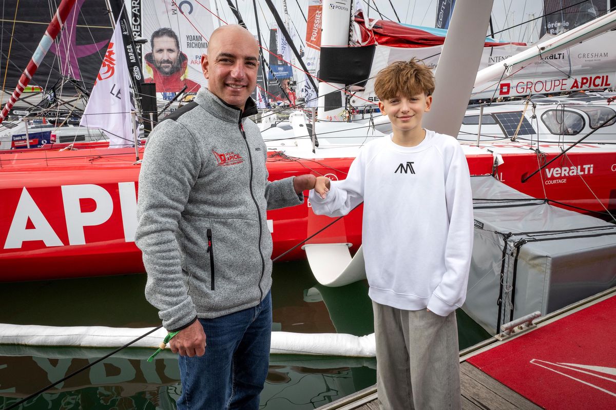 Damien Seguin et Anatole Debisschop font un check avec leurs mains handicapées devant le bateau Apicil aux Sables d’Olonne.