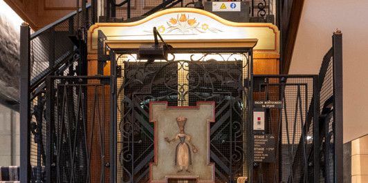 Historischer Aufzug im Park Hotel Gstaad mit Holzkabine und reich verzierter schmiedeeiserner Umrandung.
