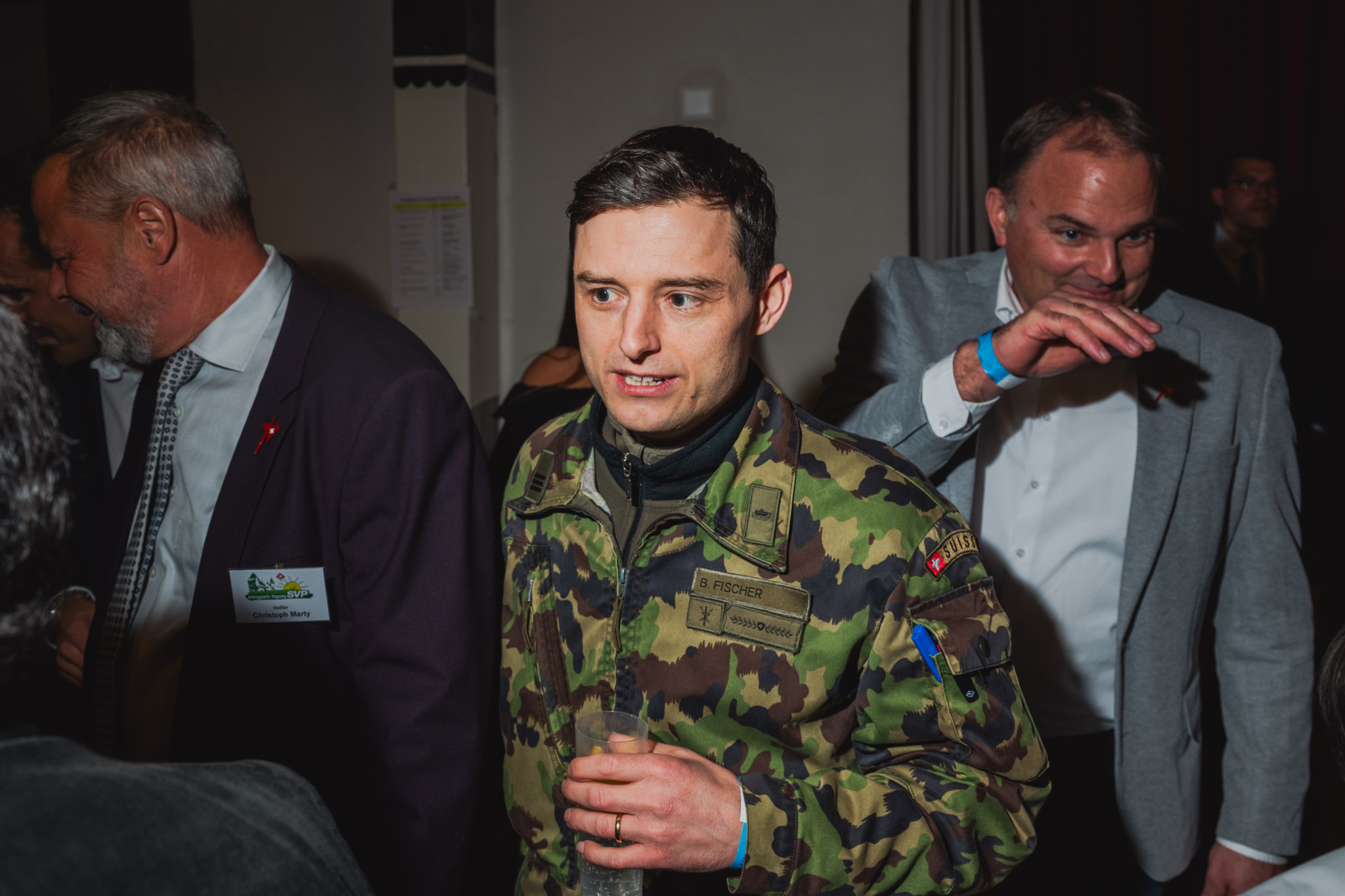 Ein Mann in einer Tarnuniform steht inmitten einer Gruppe von Menschen auf einer Veranstaltung.