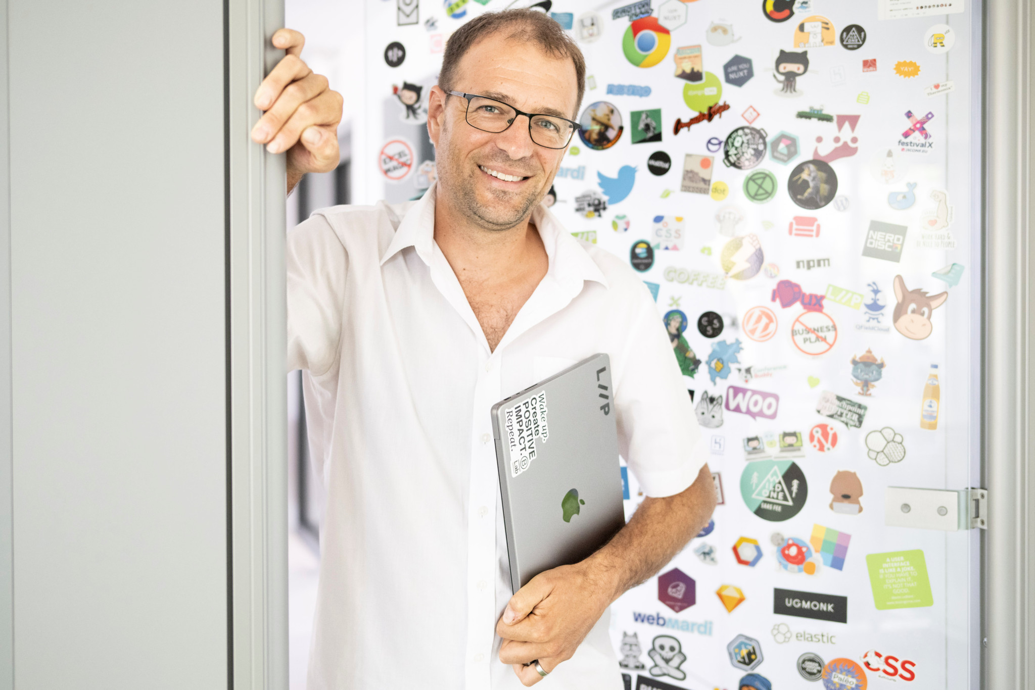David Jeanmonod, informaticien à Lausanne, tient un ordinateur portable avec de nombreux autocollants technologiques en arrière-plan.