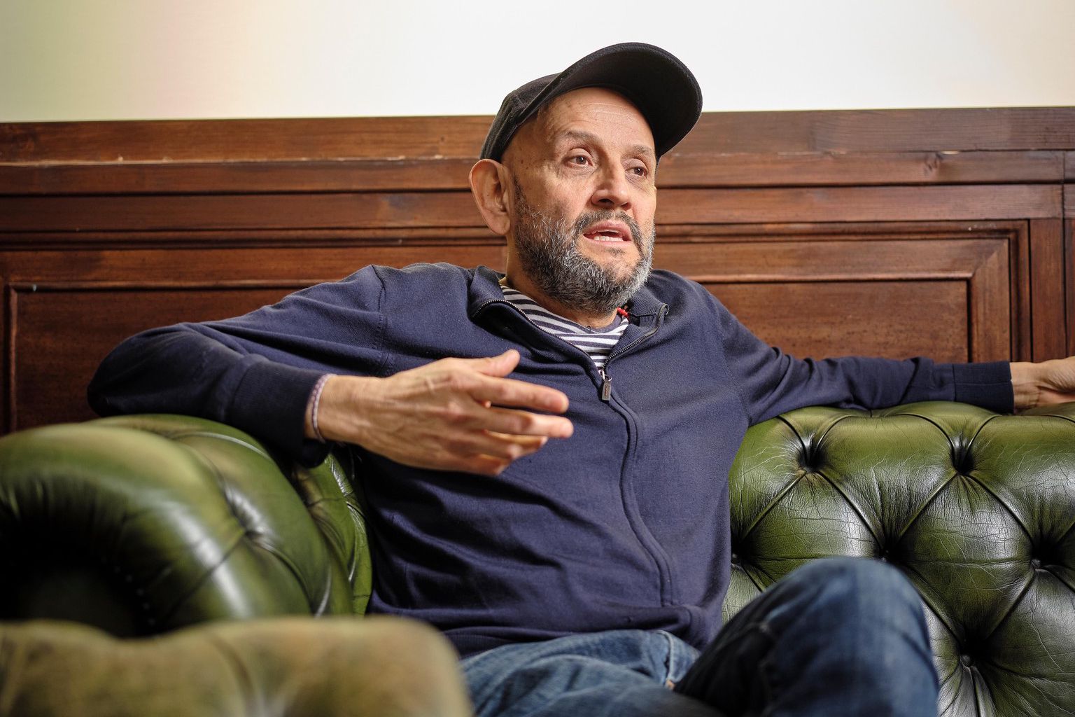 Omar Porras, metteur en scène et acteur, assis sur un canapé en cuir vert à Renens. 