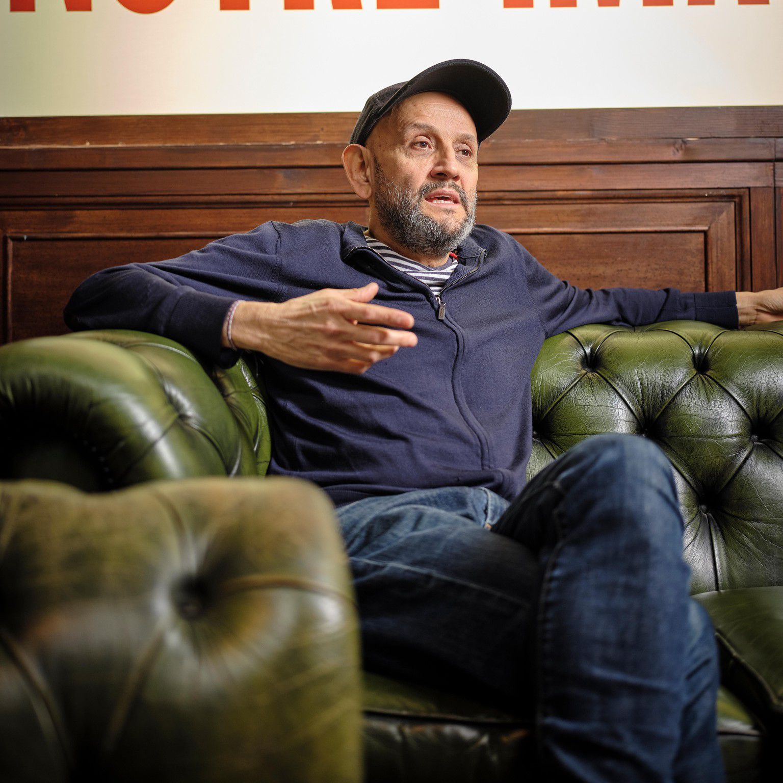 Omar Porras, metteur en scène et acteur, assis sur un canapé en cuir vert à Renens. 
