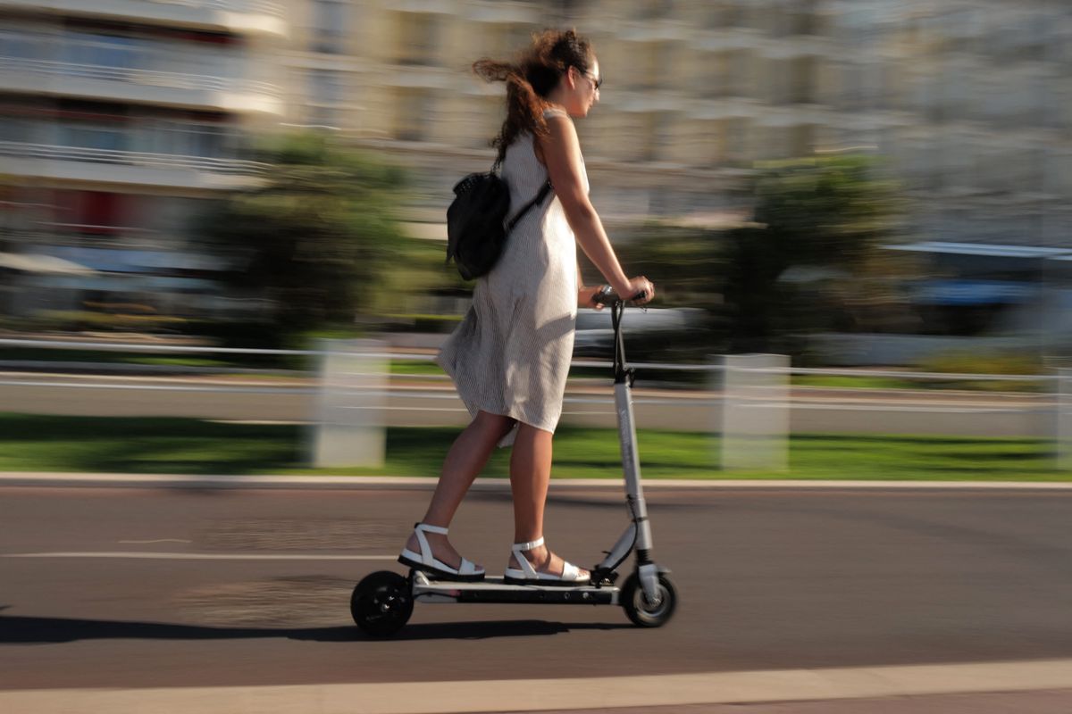 A local resident rides an electric scooter on the "Promenade des anglais" in Nice on July 11, 2022. (Photo by Valery HACHE / AFP)