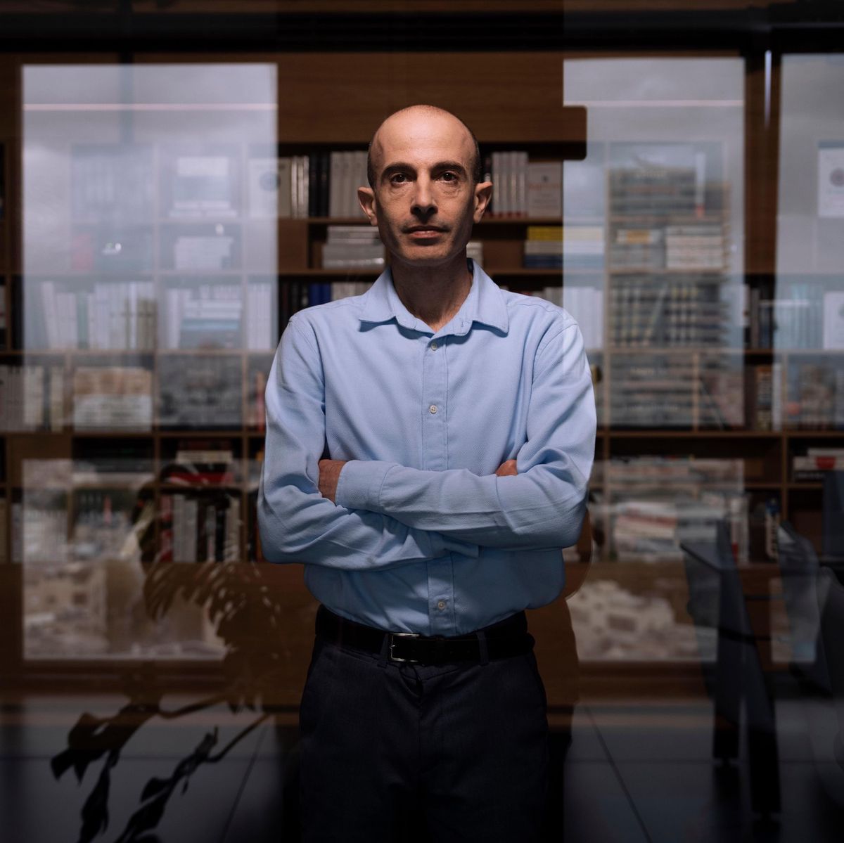 Yuval Noah Harari dans son bureau à Tel Aviv, les bras croisés devant une baie vitrée, le 30 mars 2023.