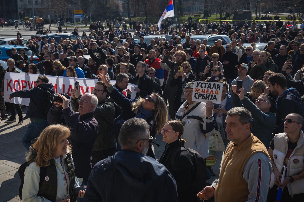 Des manifestants serbes de l’opposition devant le Parlement à Belgrade, le 4 mars 2025, brandissant des banderoles et des panneaux, entourés par une foule dense. Un drapeau serbe est visible en arrière-plan. Photo par Andrej ISAKOVIC / AFP.
