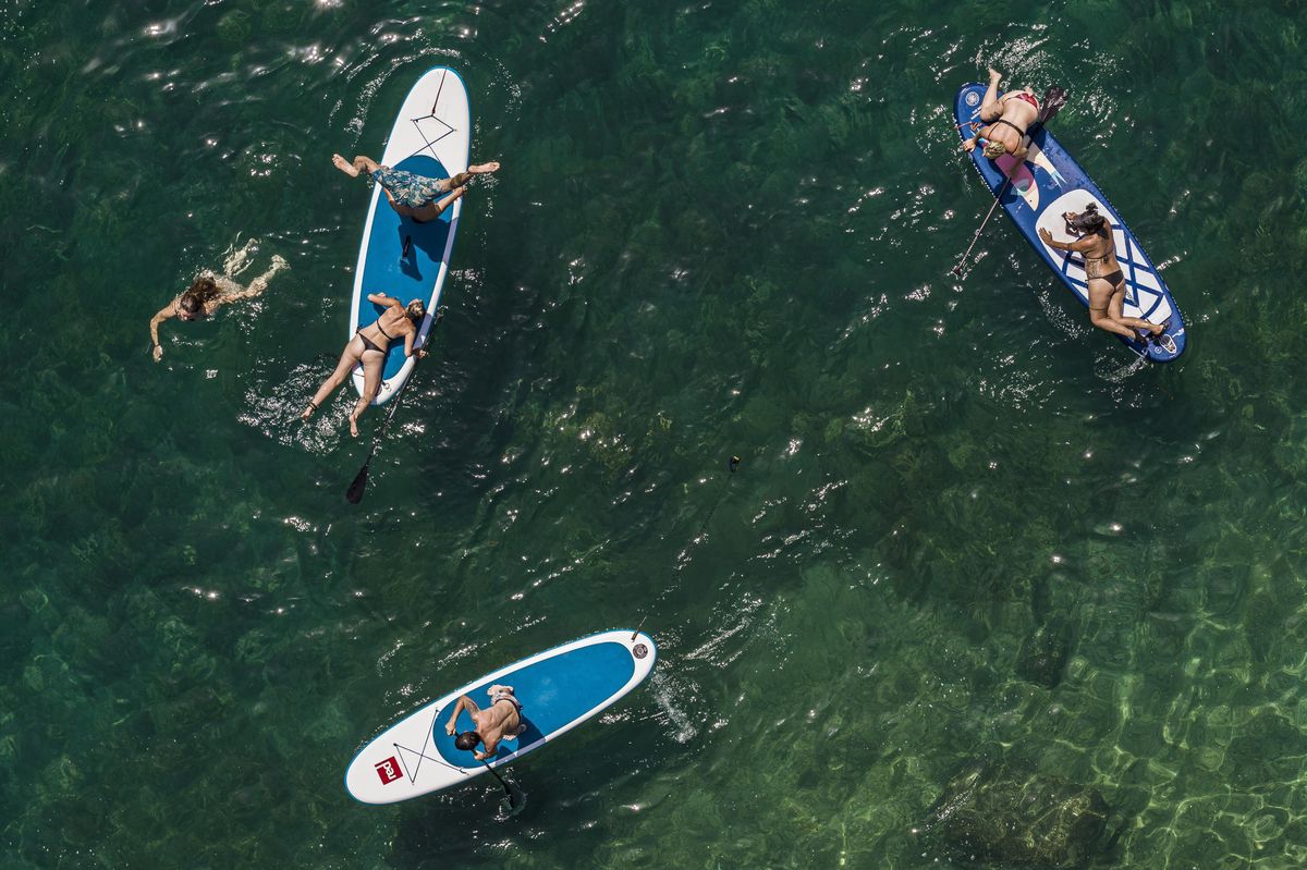 People enjoy the warm weather with their paddle boards on lake Geneva as a heat wave reaches the country, in Chardonne, Switzerland, Saturday, June 18, 2022. (KEYSTONE/Valentin Flauraud)