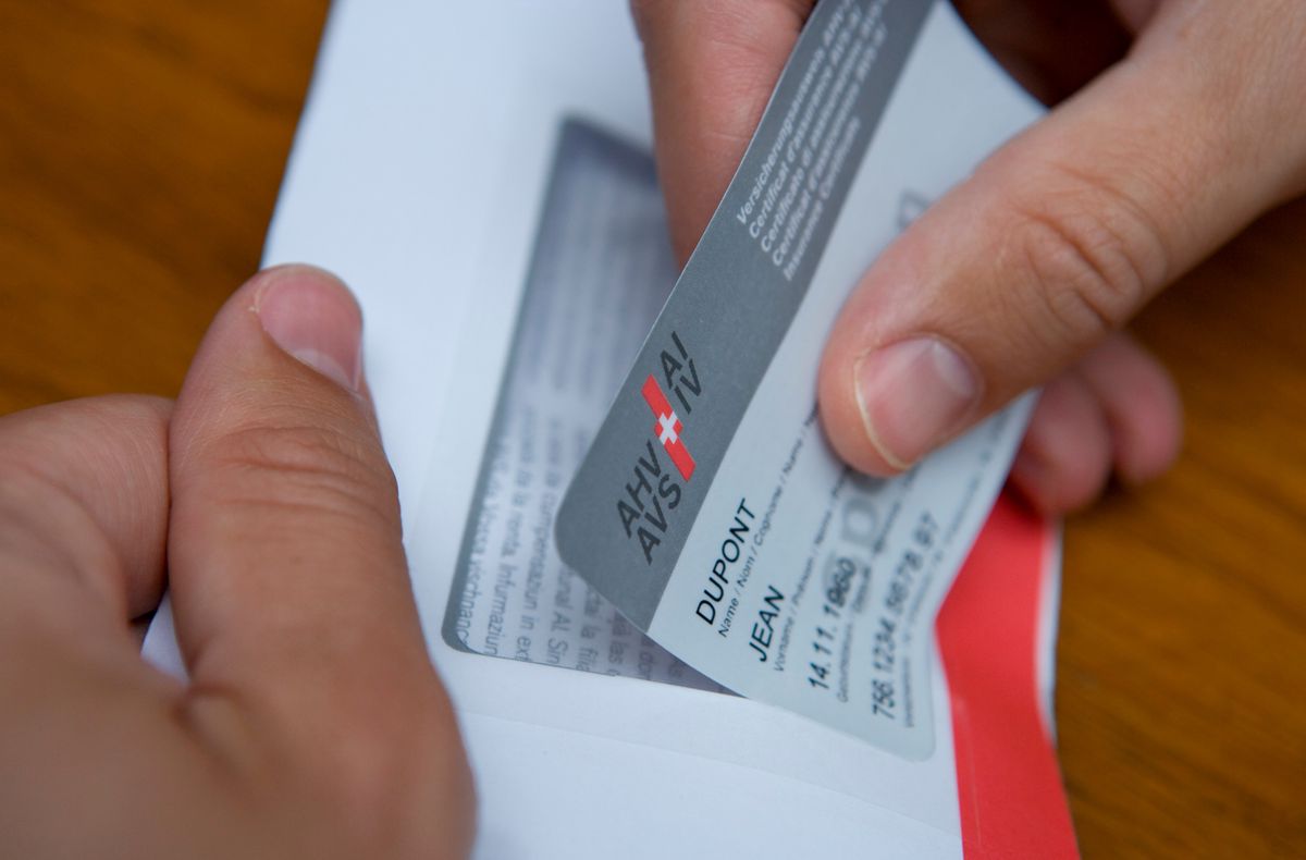 Un homme retire un prototype du nouveau certificat d'assurance AHV-IV d'une feuille de papier perforée, photographié dans un studio à Zurich, Suisse, le 30 mai 2008. La nouvelle carte à 13 chiffres entre en vigueur en juillet 2008.