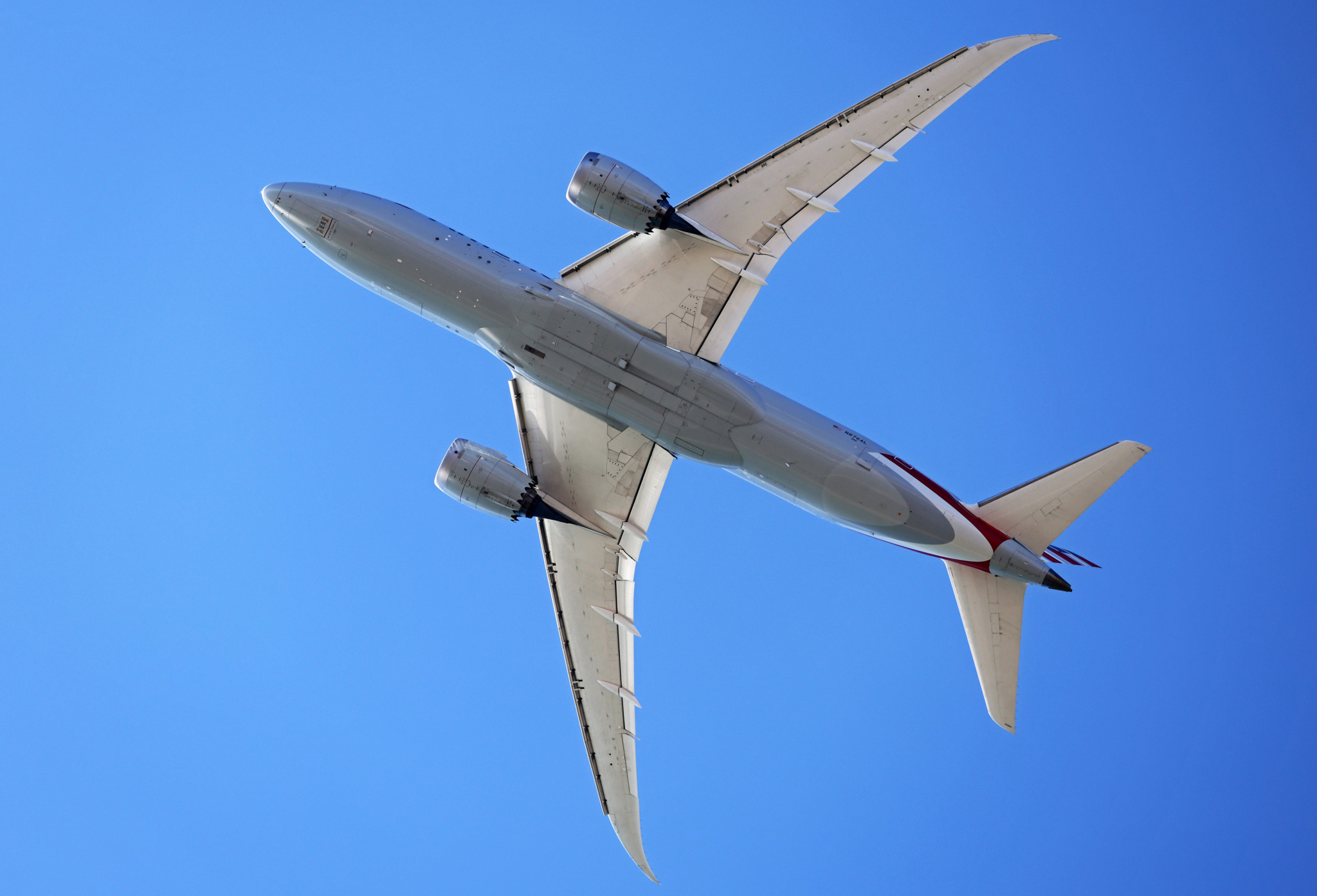 Ein American Airlines Boeing 787-8 Dreamliner fliegt über Barcelona, Spanien, mit klarem blauem Himmel im Hintergrund am 1. April 2025.
