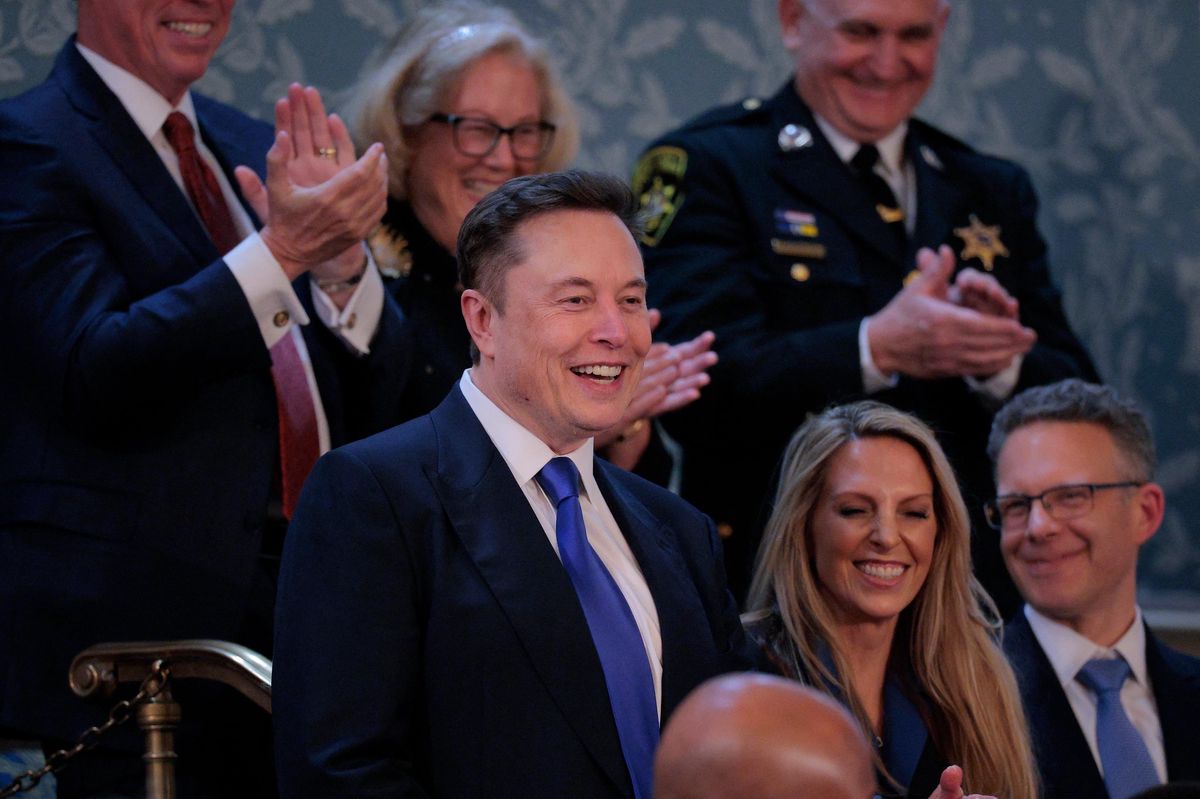 Elon Musk assiste à l’allocution du Président Trump au Congrès à Washington, DC, entouré de personnes applaudissant.