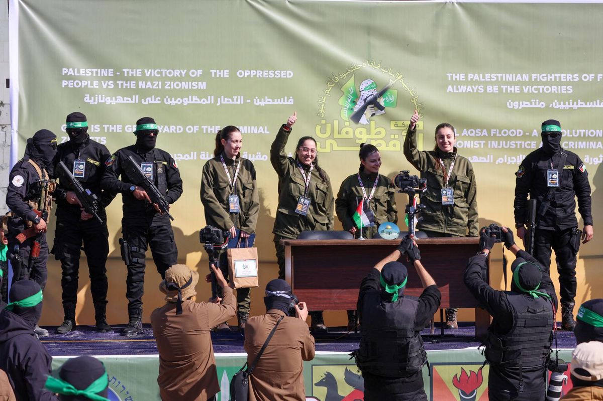Groupe de personnes en uniforme posant sur une scène avec un arrière-plan vert portant des slogans en anglais et en arabe, liés à la Palestine.