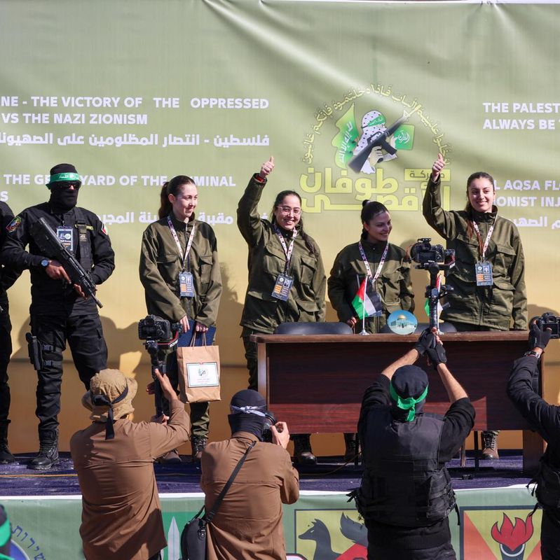 Groupe de personnes en uniforme posant sur une scène avec un arrière-plan vert portant des slogans en anglais et en arabe, liés à la Palestine.