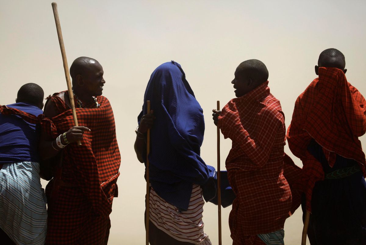 Des hommes Maasai couvrent leurs visages lors d’une tempête de sable près du Serengeti en Tanzanie, août 2013.