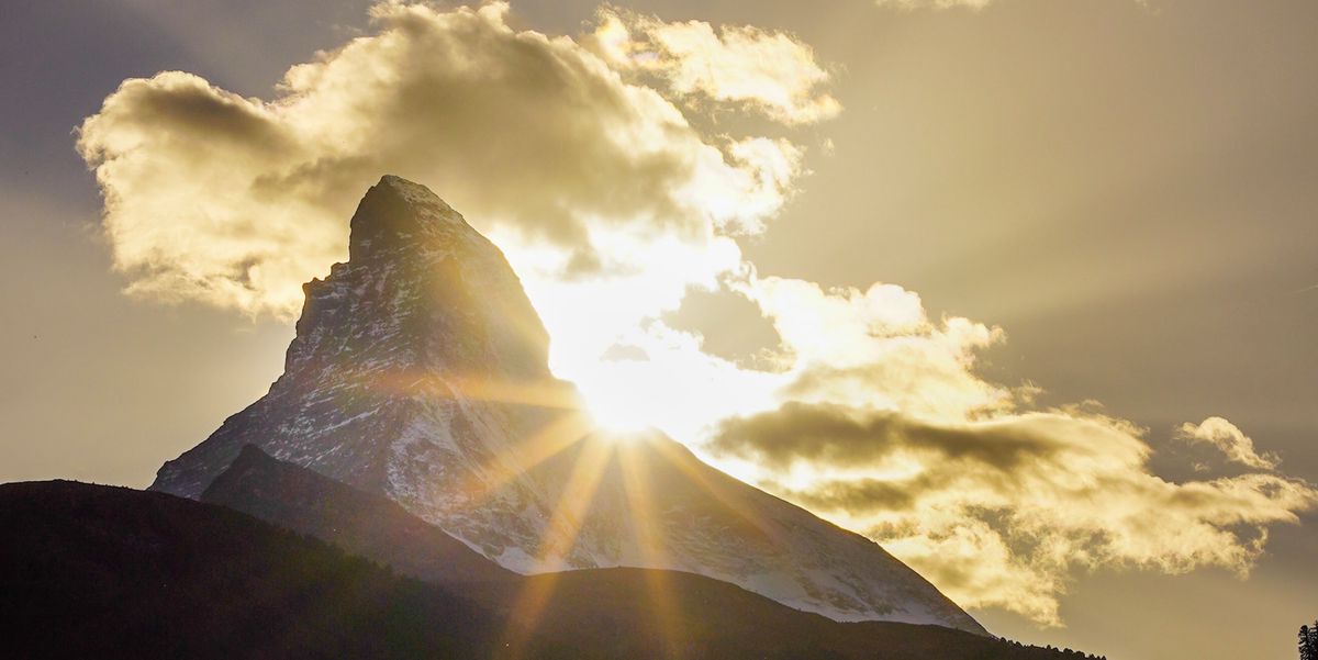 Le Cervin éclairé par le soleil couchant, avec des nuages entourant le sommet de la montagne.