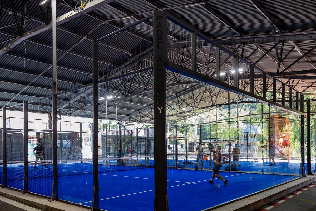 Terrains de padel couverts aux Halles de la Jonction à Genève, ancien dépôt des Transports publics genevois, avec des joueurs en action.