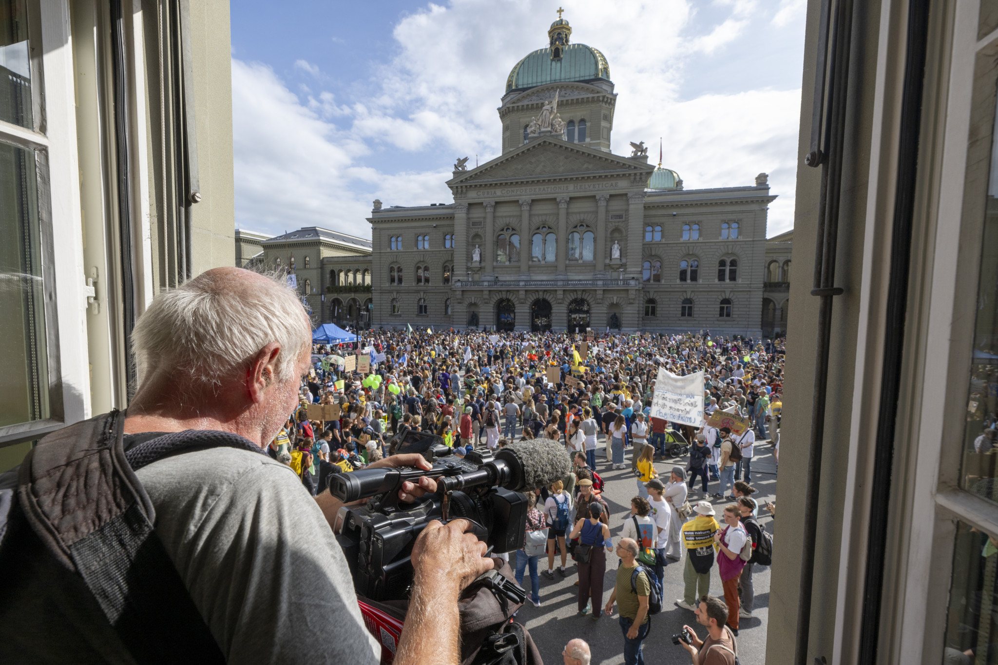 Kameramann filmt nationale Klimademo auf dem Bundesplatz in Bern mit zehntausenden Teilnehmern, 30. September 2023.