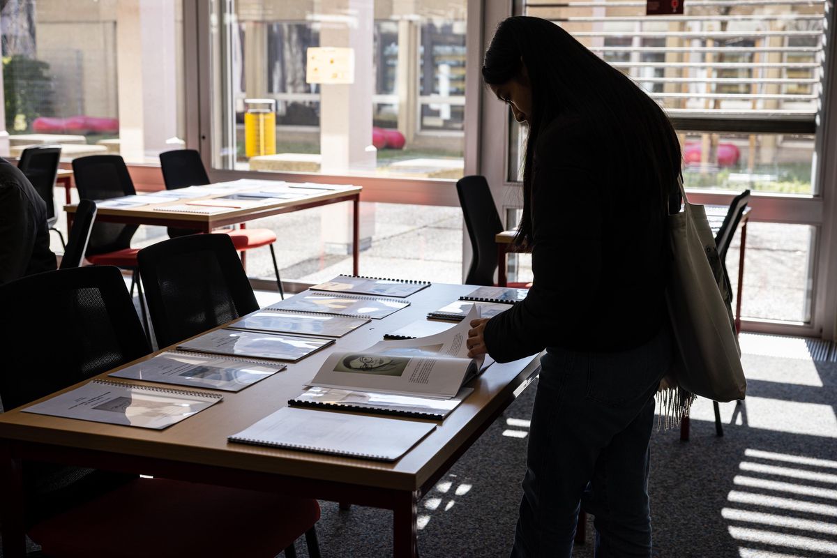 Élève examinant un travail de maturité exposé à la bibliothèque du collège Voltaire à Genève, février 2023.