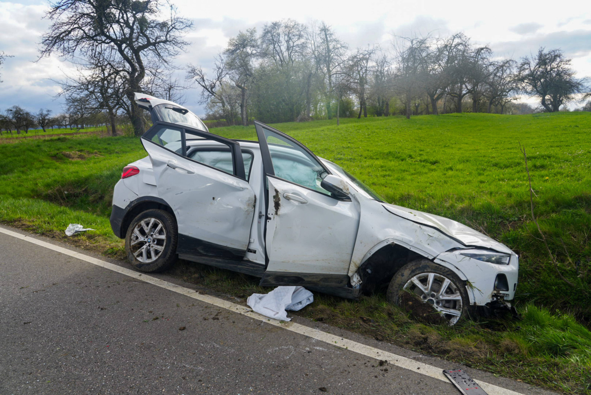 Une BMW blanche gravement accidentée dans un fossé près de Bad Boll, portes ouvertes et carrosserie déformée, après qu’un conducteur de 71 ans s’est endormi au volant.