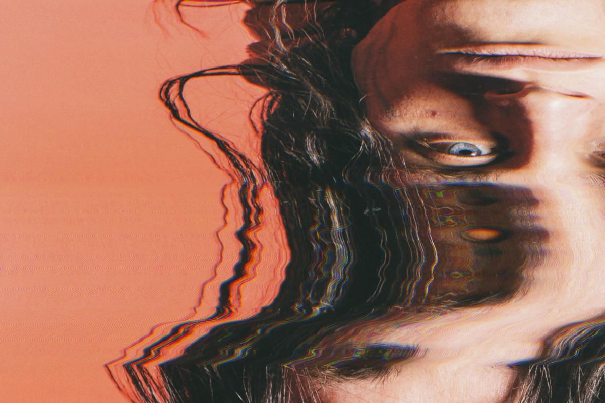 Image artistique montrant un visage brouillé avec des effets de texture et des distorsions sur un fond orange.