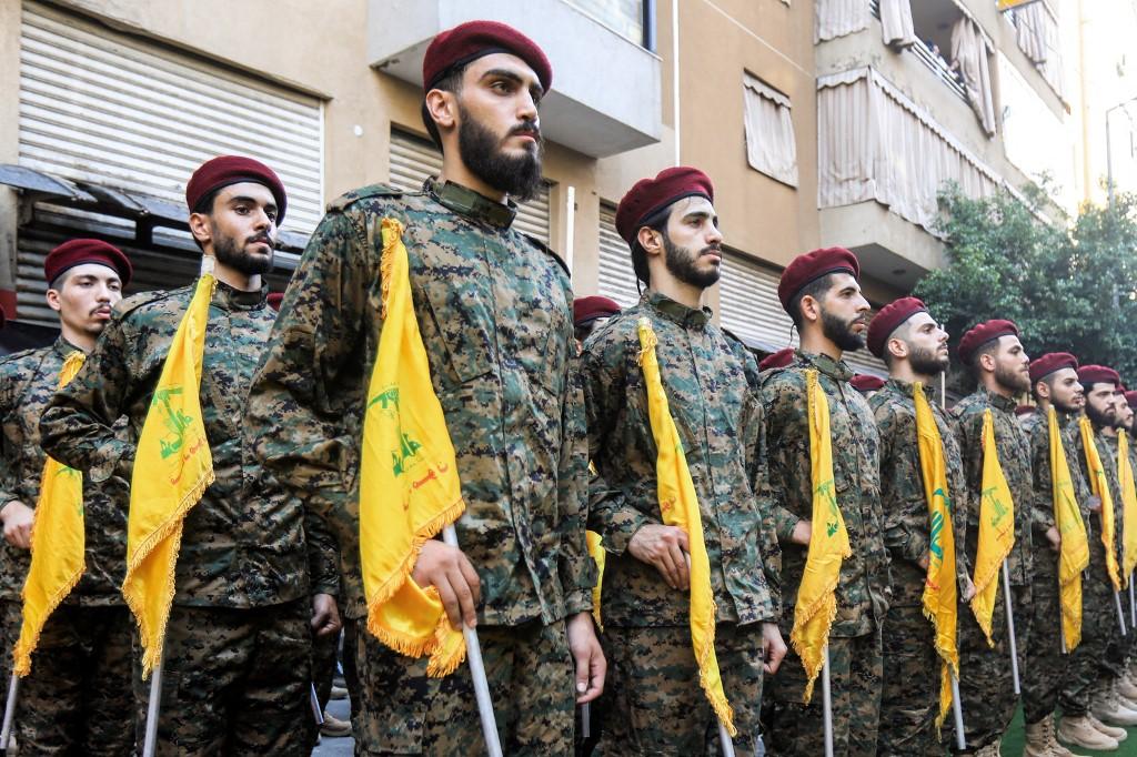Des combattants du mouvement chiite libanais Hezbollah assistent aux funérailles du commandant militaire Ibrahim Aqil dans la banlieue sud de Beyrouth. Les soldats sont alignés en uniforme avec des drapeaux jaunes du Hezbollah.