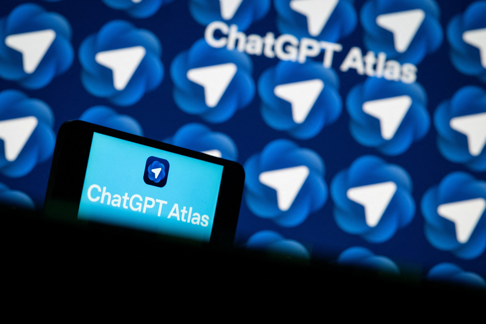 Logo du navigateur web IA ChatGPT Atlas affiché sur un smartphone et un écran en arrière-plan, à Mulhouse.