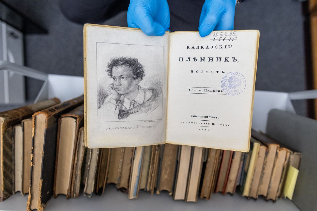 A university employee presents a fake copy of a first edition of the 1822 book 'Kavkazskiy plennik: povest' by Alexander Pushkin at the University of Warsaw library in Warsaw, Poland on November 14, 2023. A spate of thefts of rare Russian classics worth millions of euros from libraries across Eastern Europe has left a trail that points all the way to Moscow. (Photo by Wojtek Radwanski / AFP)