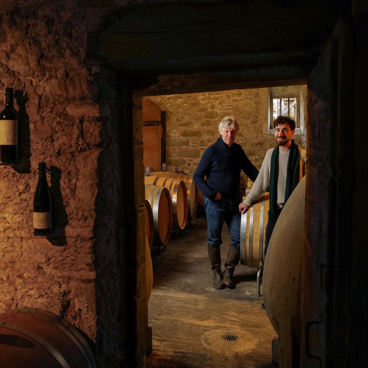 Jean-Pierre Pellegrin et son fils dans une cave à Genève, entourés de tonneaux de vin.
