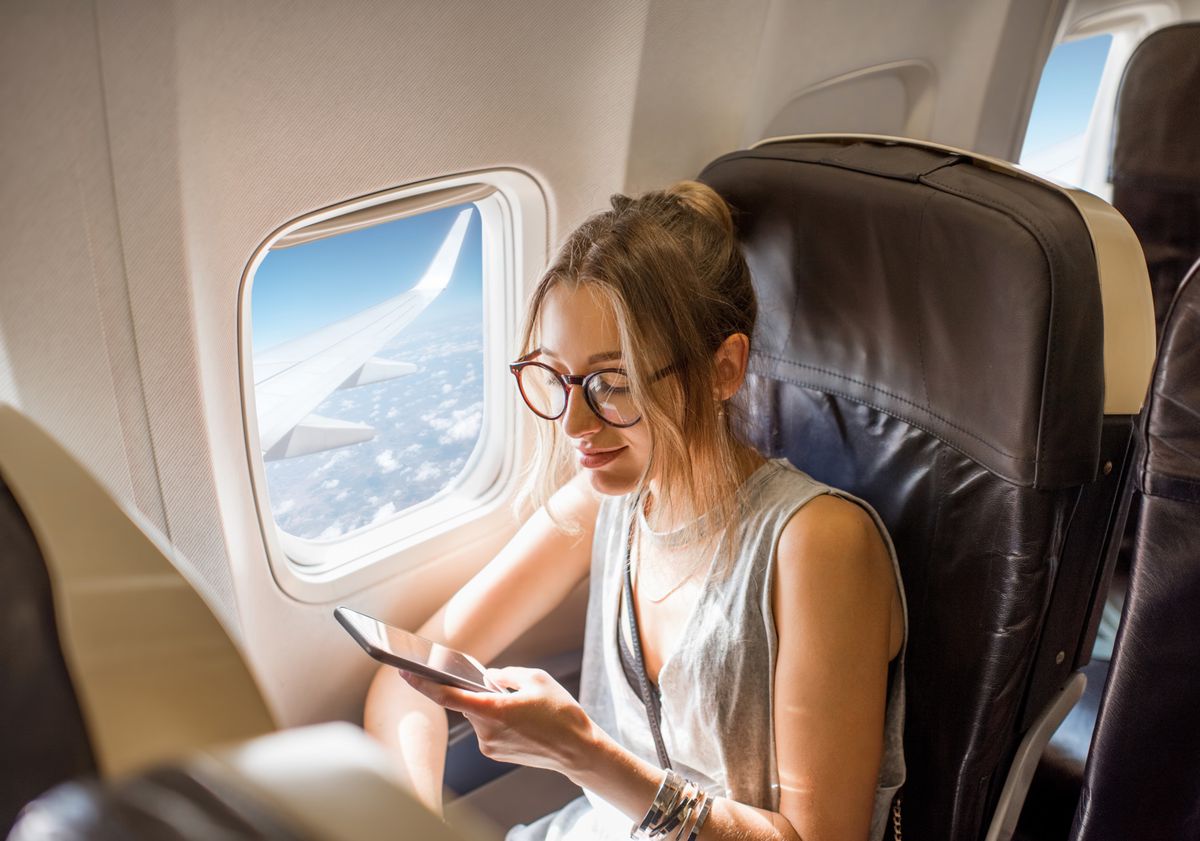 Jeune femme assise dans un avion avec un téléphone portable