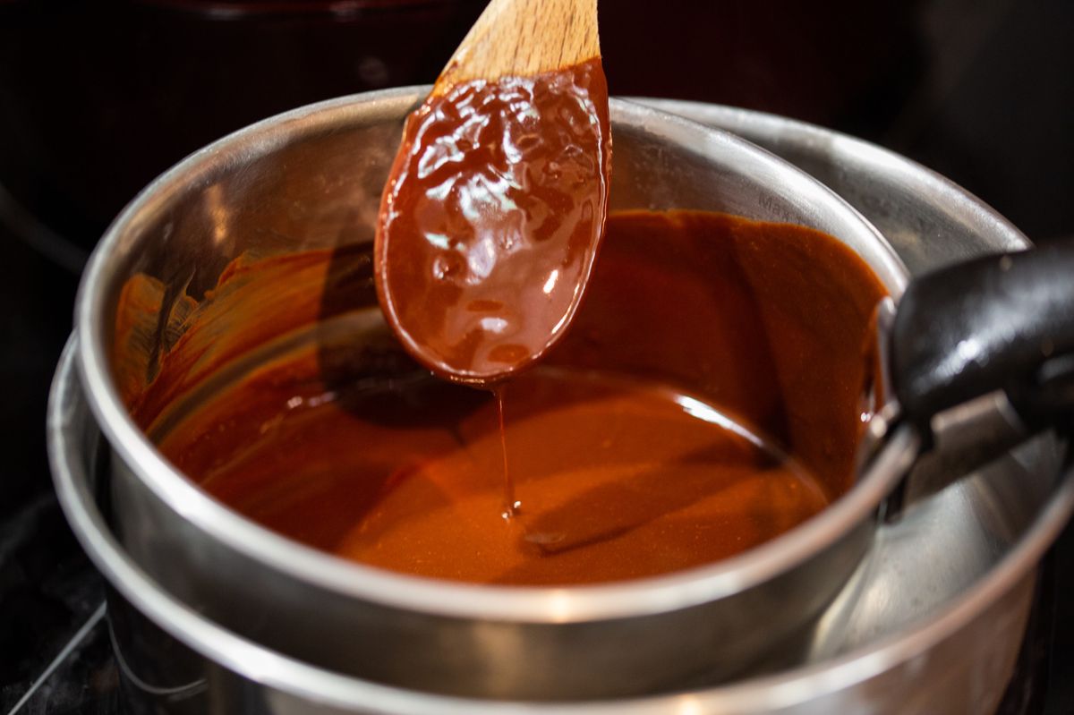 Cette photographie présente des plans rapprochés d'une personne en train de pâtisser. Chocolat fondu, cuisine électrique, cuisson au bain marie
