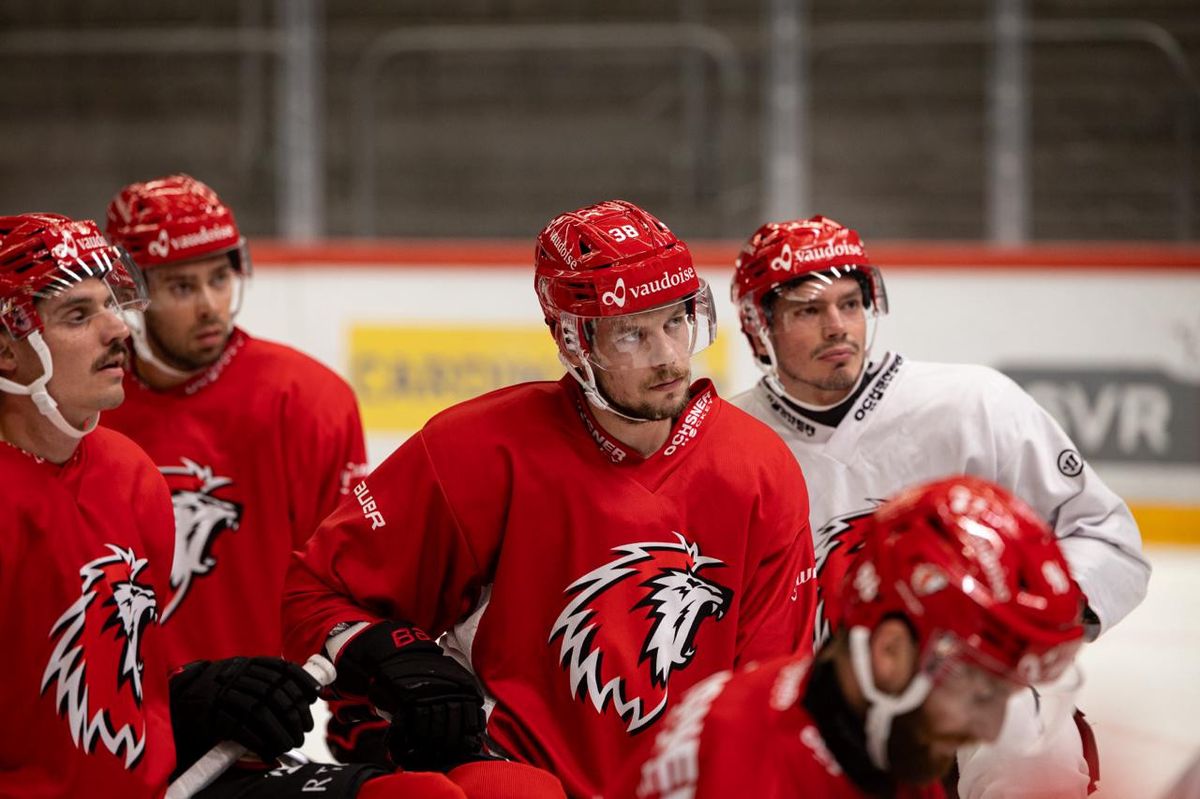 Plusieurs joueurs de hockey sur glace en maillots rouges et blancs avec des casques rouges, lors d'un entraînement sur glace.