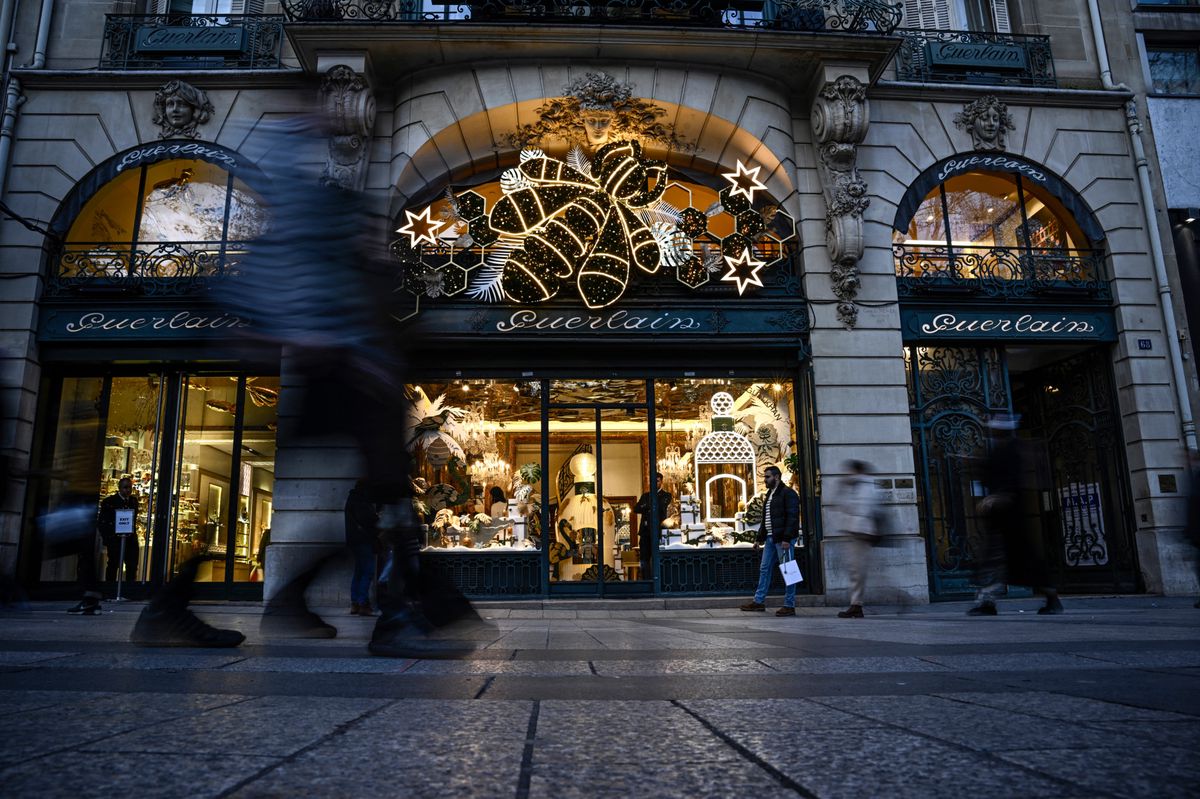 Pedestrians walk past a Guerlain cosmetics luxury cosmetic shop display with Christmas decorations on the Champs Elysee avenue, in Paris, on December 15, 2023. (Photo by JULIEN DE ROSA / AFP)