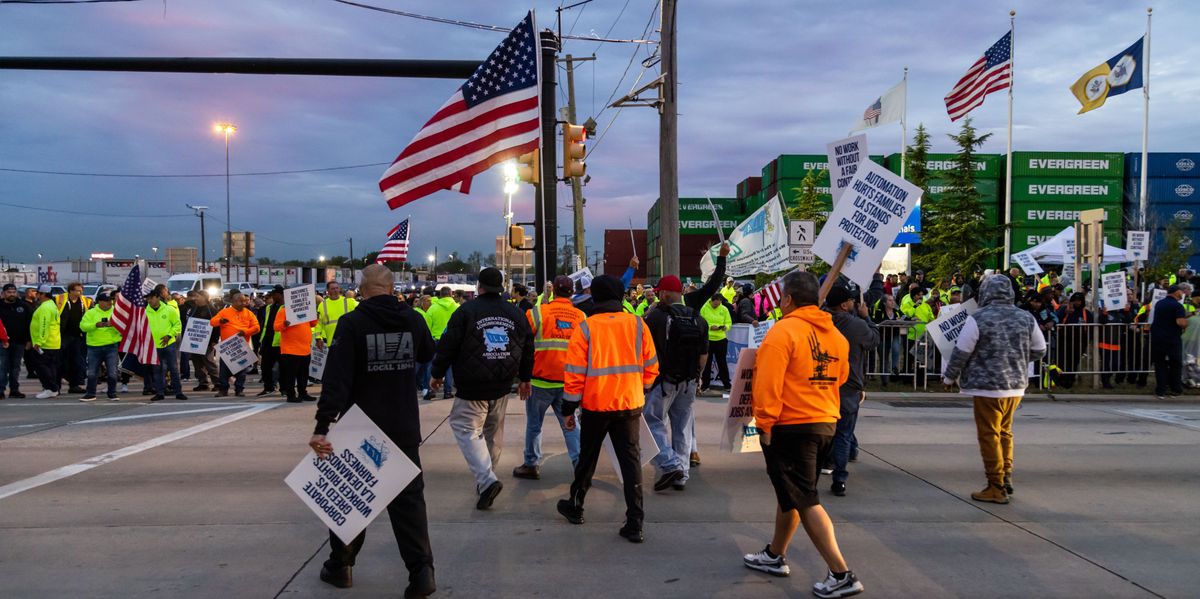 Streikende Hafenarbeiter protestieren vor dem APM-Containerterminal im Hafen von Newark, USA, mit Plakaten und Flaggen.