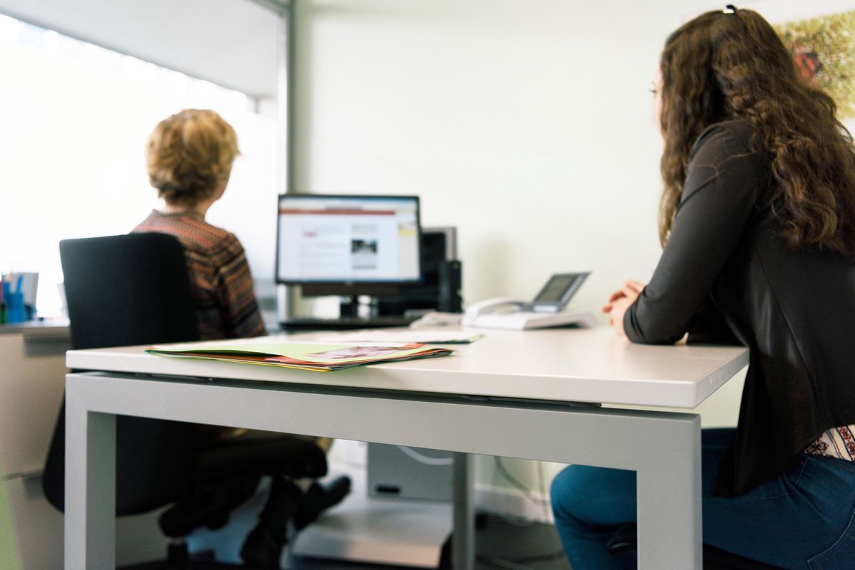 Deux personnes en consultation au centre social Albisriederhaus à Zurich, assises à un bureau, discutant face à un écran d'ordinateur.