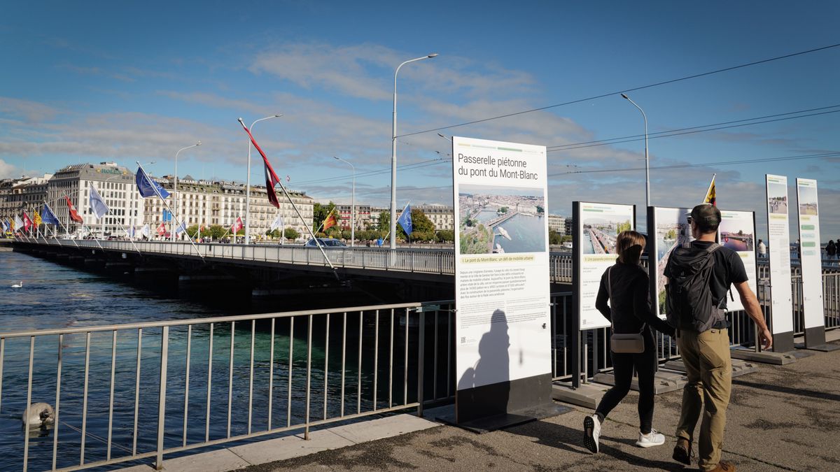 Des passants regardent des panneaux explicatifs sur le projet de la passerelle du pont du Mont-Blanc à Genève, avec des bâtiments en arrière-plan.