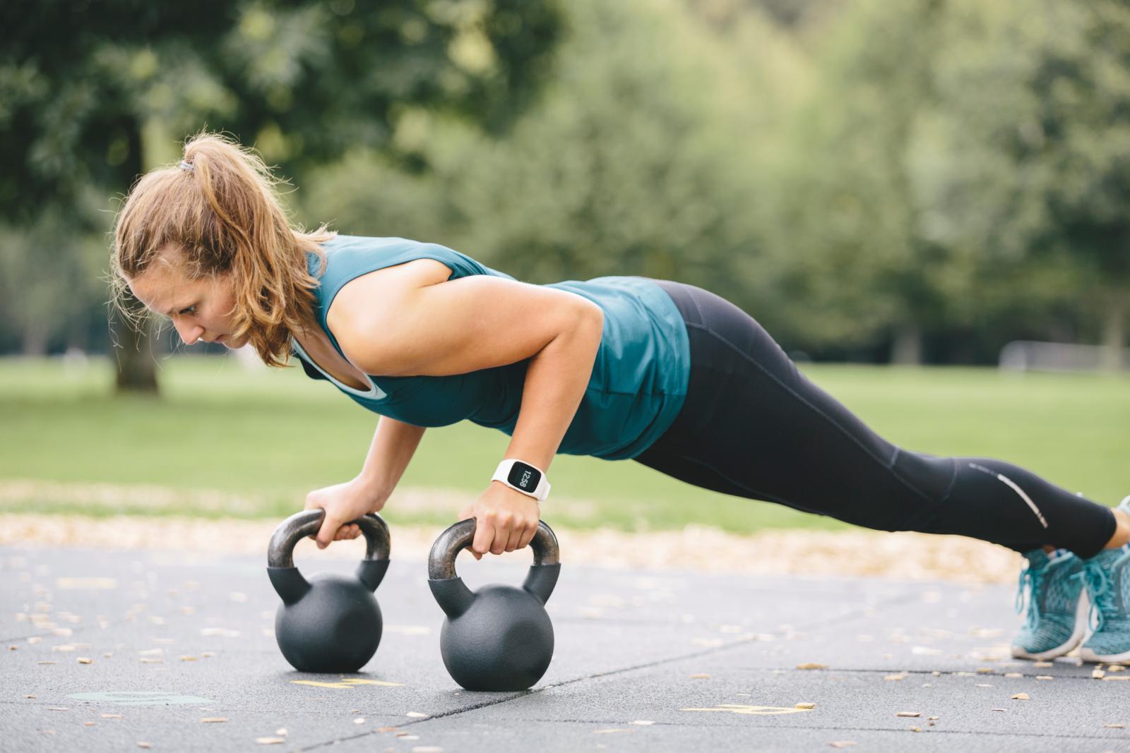 sporty lady performing pushups on dumbells.