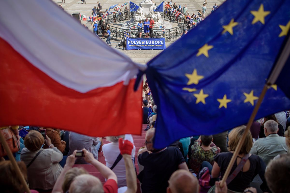 epa06128281 Participants of the monthly pro-European Union rally titled 'Pulse of Europe', hold flags in the national colors of Poland (L), and the European flag in front of the concert hall at the Gendarmenmarkt place in Berlin, Germany, 06 August 2017. The citizen's initiative was founded to encourage EU citizens to promote a 'pan-European' identity. EPA/CLEMENS BILAN