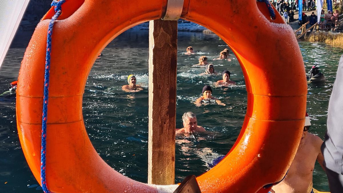 Teilnehmende des 7. Blausee-Schwimmens schwimmen im kalten Wasser, aufgenommen durch einen orangen Rettungsring. Die Sicherheit steht im Vordergrund.