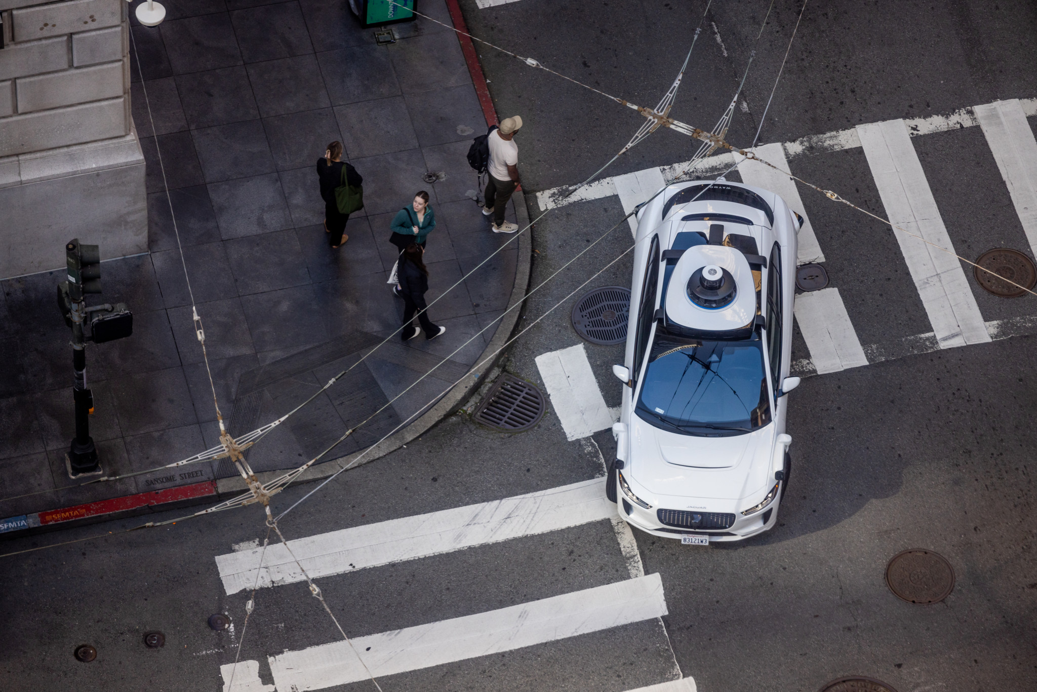 Blick von oben auf ein selbstfahrendes Waymo-Auto in der Innenstadt von San Francisco auf der Kreuzung Bush und Sansome Streets.