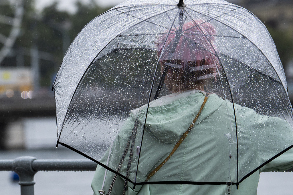 Une personne se protege avec son parapluie alors qu'elle marche sous la pluie dans les rues de Geneve, ce mercredi 4 aout 2021. (KEYSTONE/Martial Trezzini)