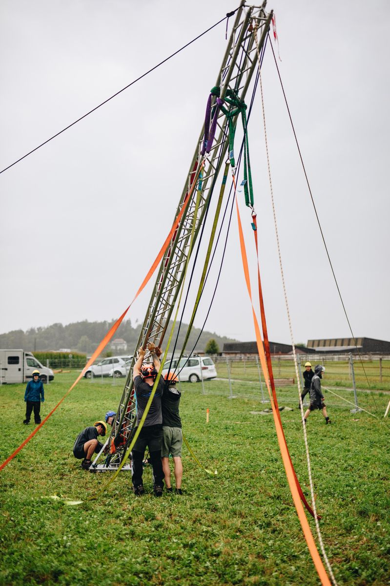 Helfer des Synergia Openair stellen einen hohen Masten auf dem Festgelände in Bisikon auf.