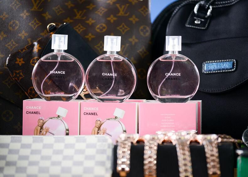 Parfums Chance de Chanel alignés devant des sacs à main de luxe et des accessoires, sur une table d’exposition.