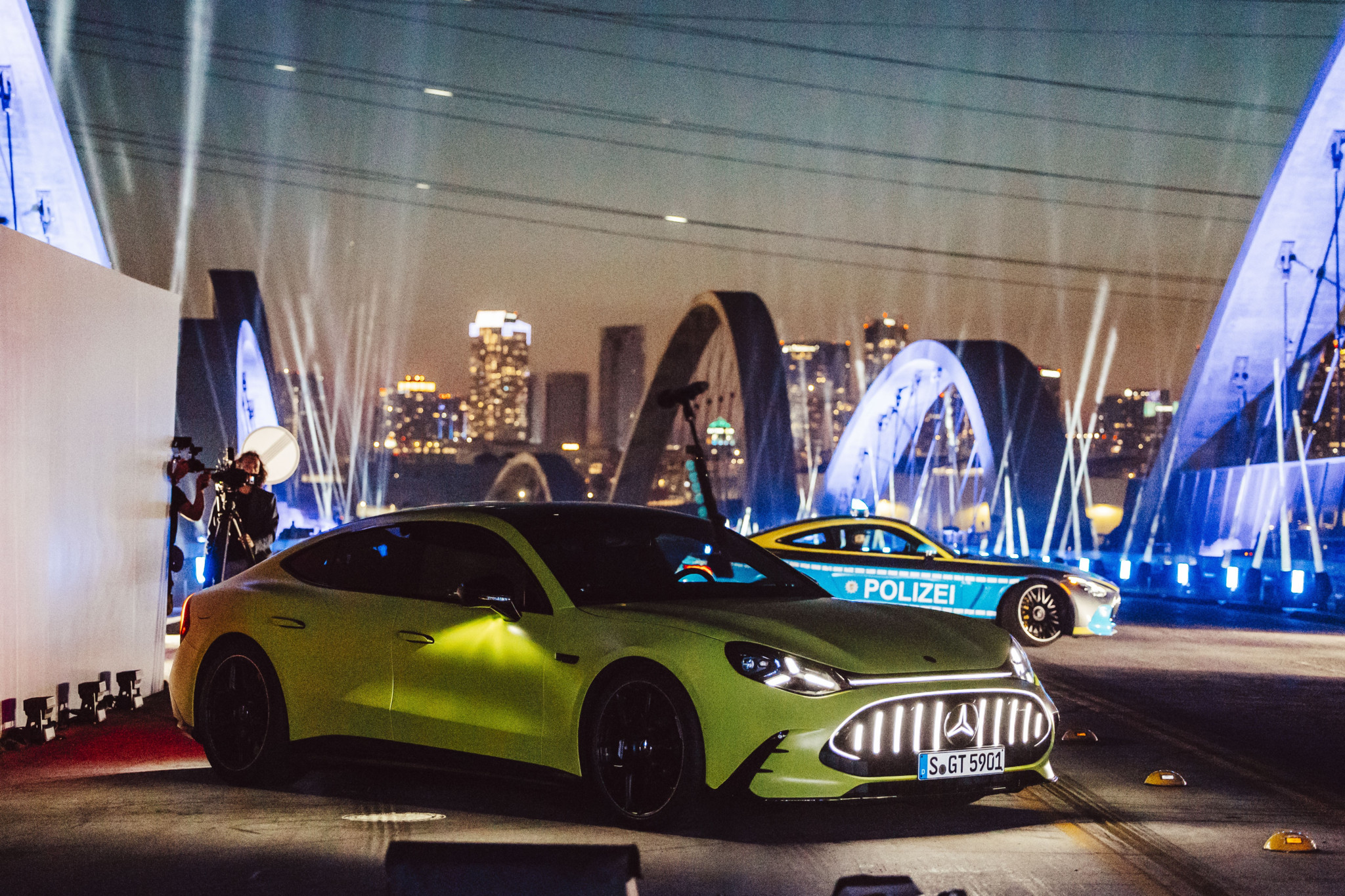 Mercedes-Premiere in Los Angeles: Zwei AMG GT Sportwagen in Neongelb und Polizei-Design vor nächtlicher Stadtkulisse mit Lichtshow.